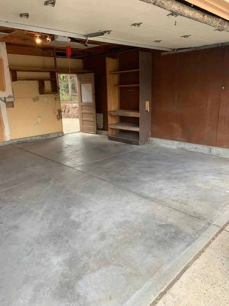 An empty garage with a clean concrete floor and built-in wood shelving