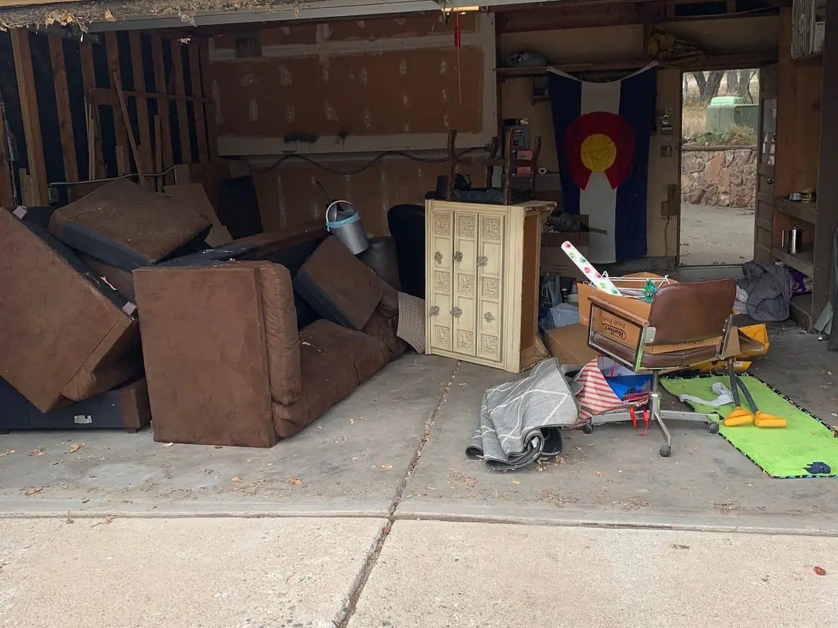 A garage with a brown sectional, cabinets and boxes
