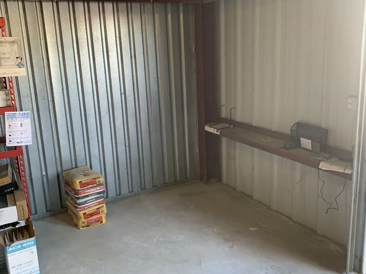 The same storage unit with the floor swept bare and only a shelf and a stack of bags left