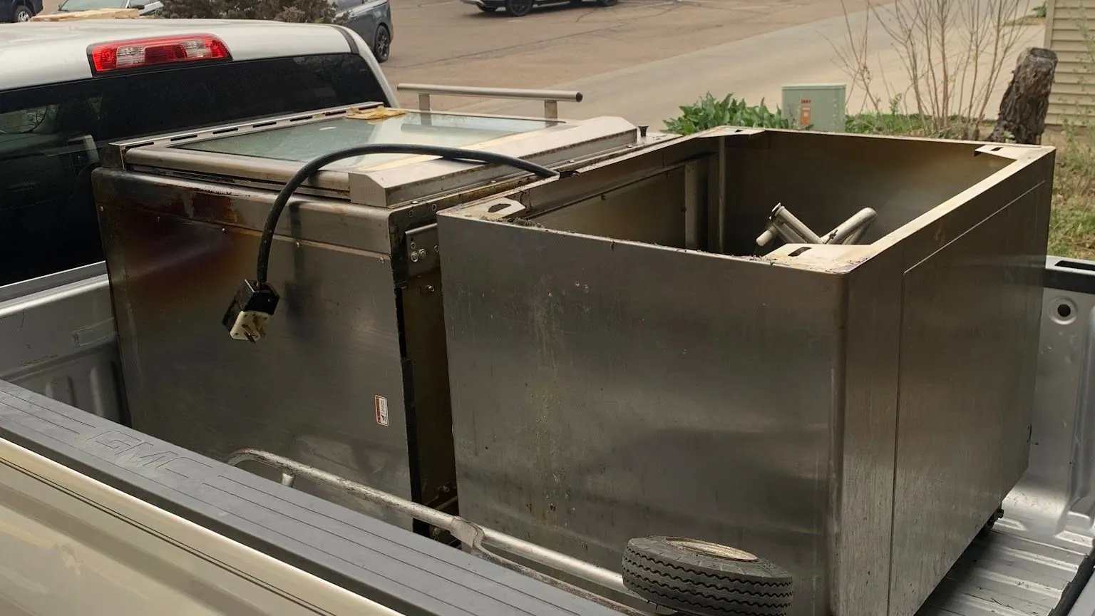 Two stainless steel commercial kitchen units in the bed of a silver pickup