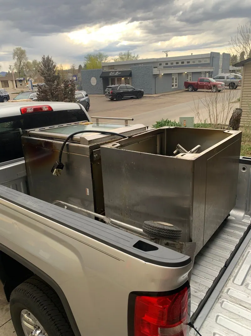 Two stainless steel commercial kitchen units in the bed of a silver pickup