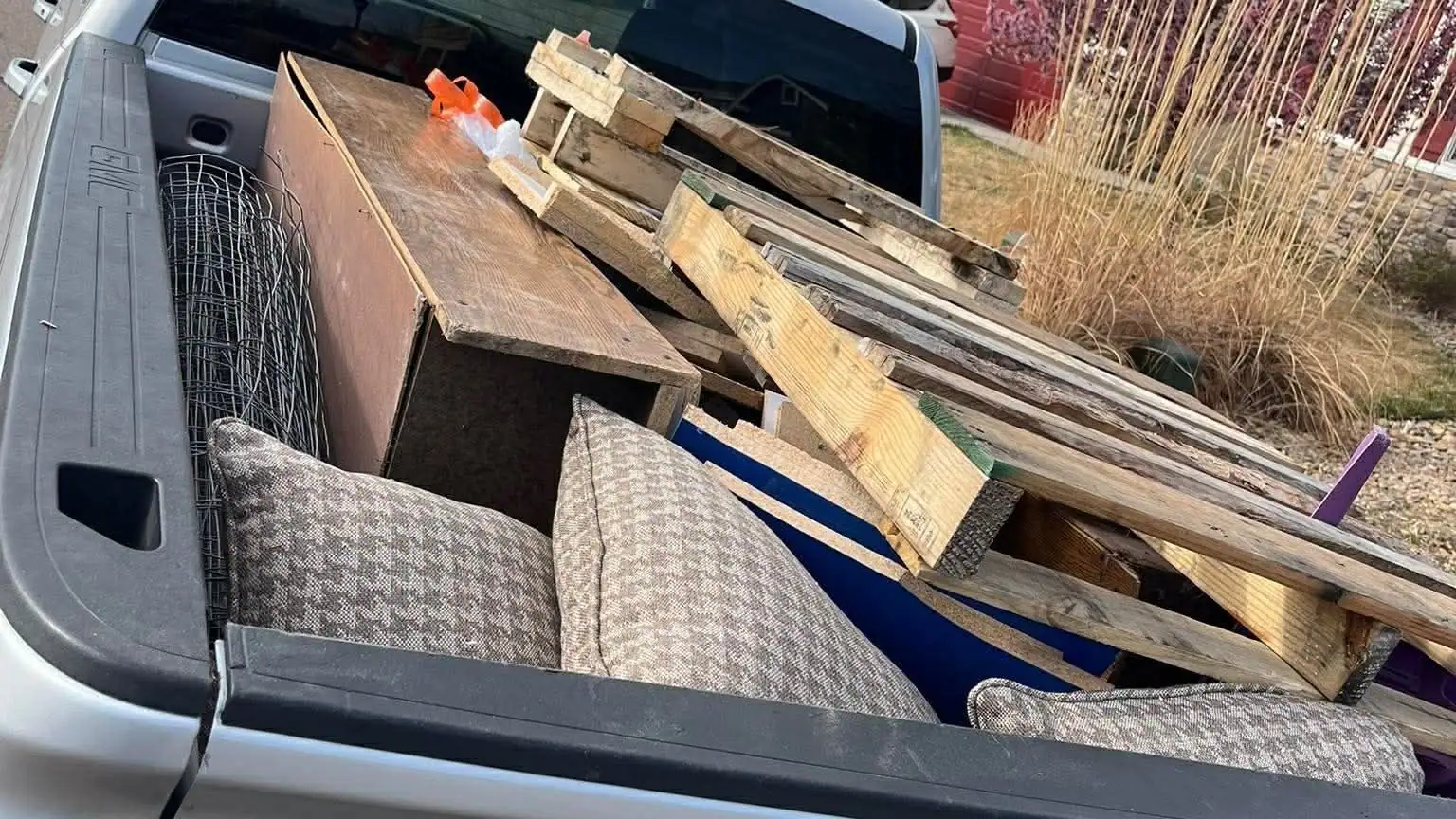 Couch cushions, a wooden cabinet and scrap lumber in the bed of a silver GMC pickup