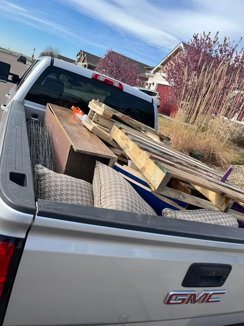 Couch cushions, a wooden cabinet and scrap lumber in the bed of a silver GMC pickup