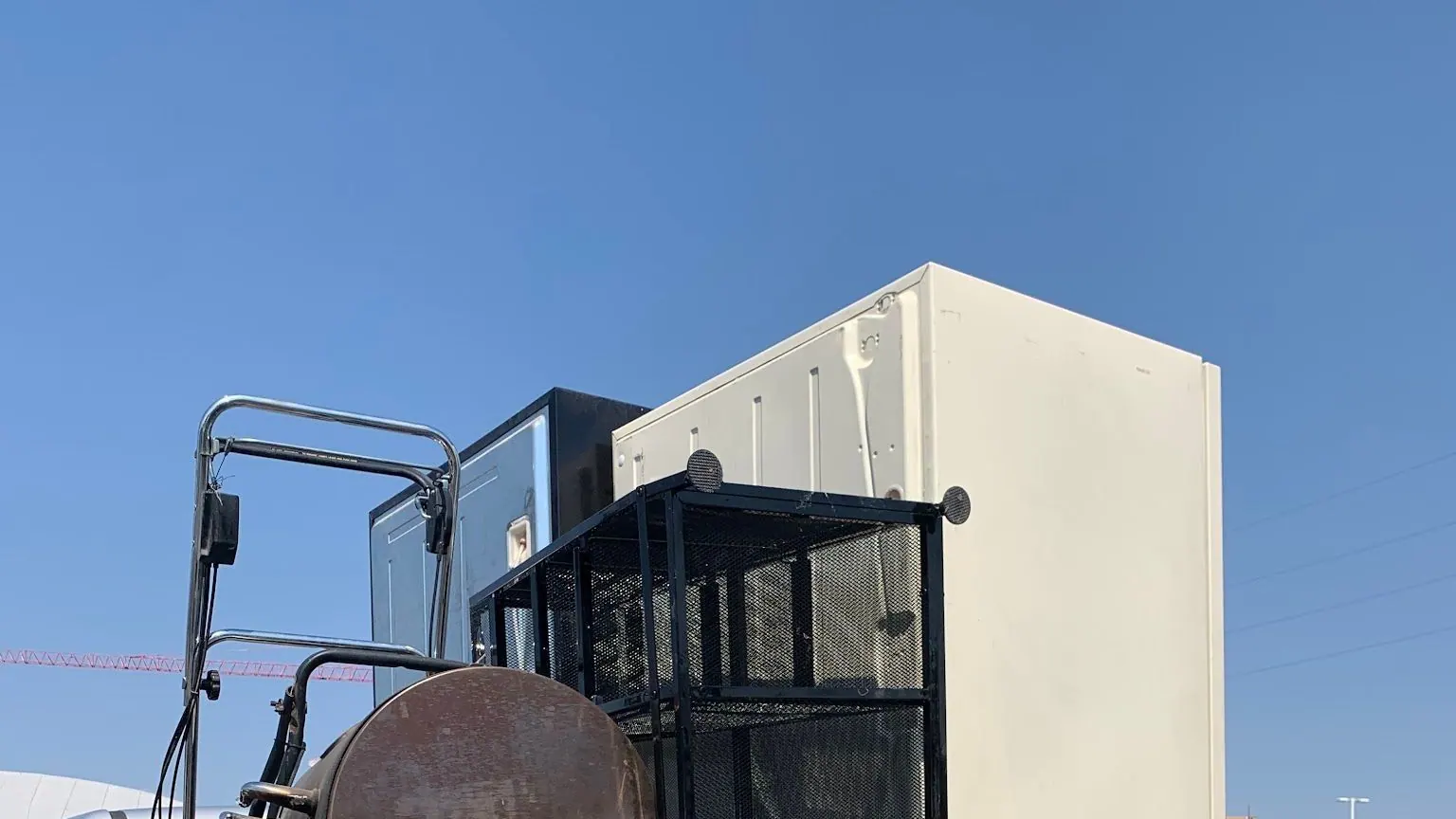 A cream refrigerator, a wire rack and a smoker loaded in the bed of a silver GMC pickup