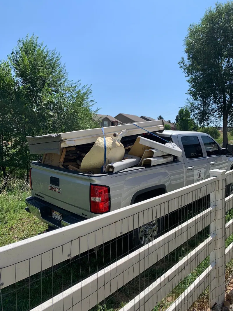 The loaded silver GMC pickup from behind, parked by a white fence