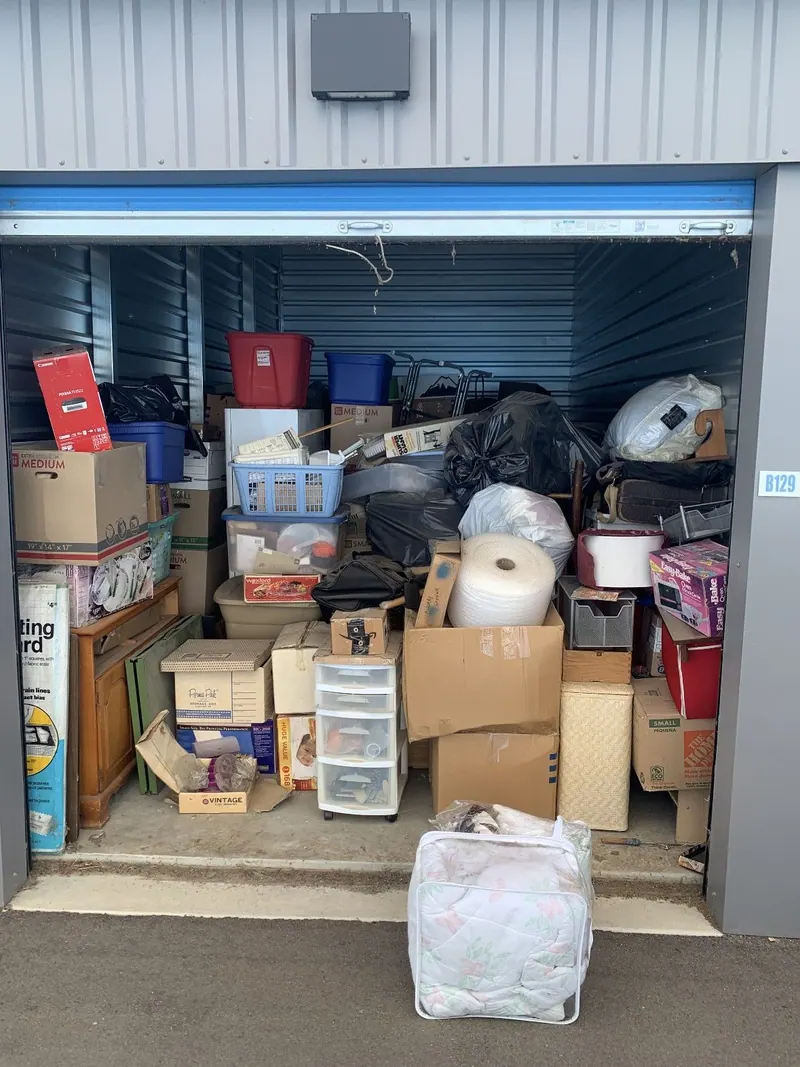 An open storage unit packed with boxes and bins and totes