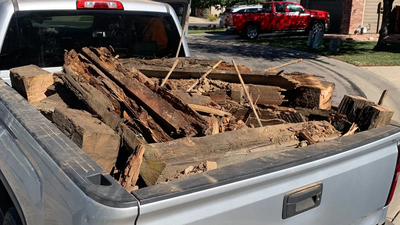 Old wooden timbers and broken lumber piled in the bed of a silver pickup
