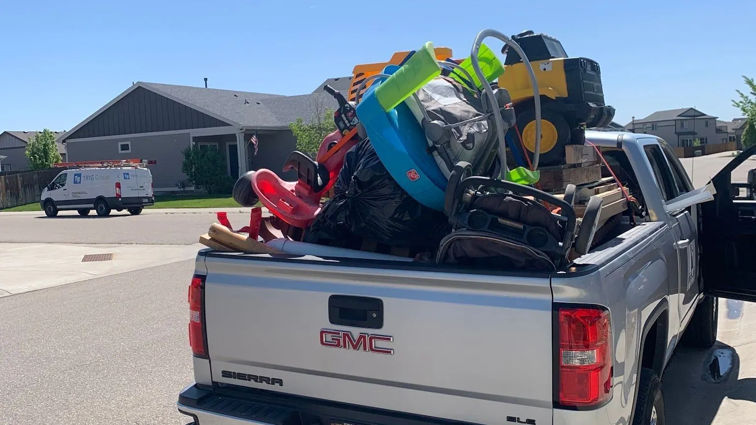 Kids' toys, a stroller and bags heaped in the bed of a silver GMC pickup