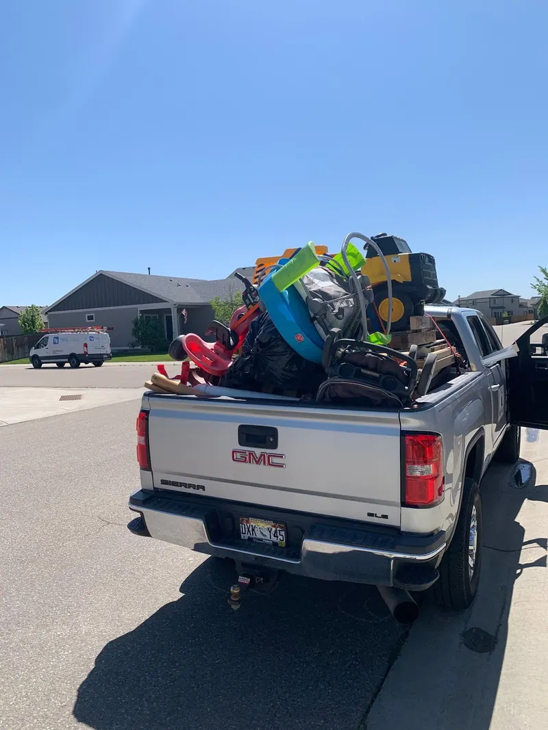 Kids' toys, a stroller and bags heaped in the bed of a silver GMC pickup
