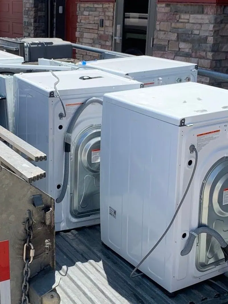 White washers and dryers stacked on an open trailer