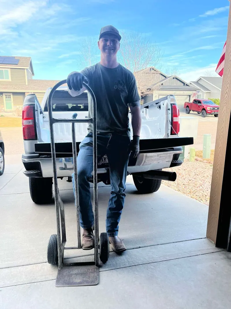 The owner with a hand truck behind the silver GMC pickup