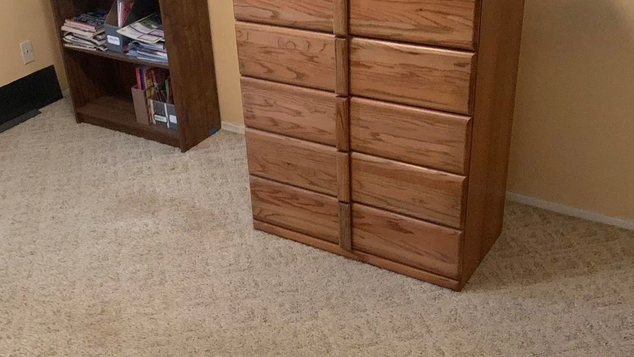 A bookshelf and an oak dresser in a carpeted room