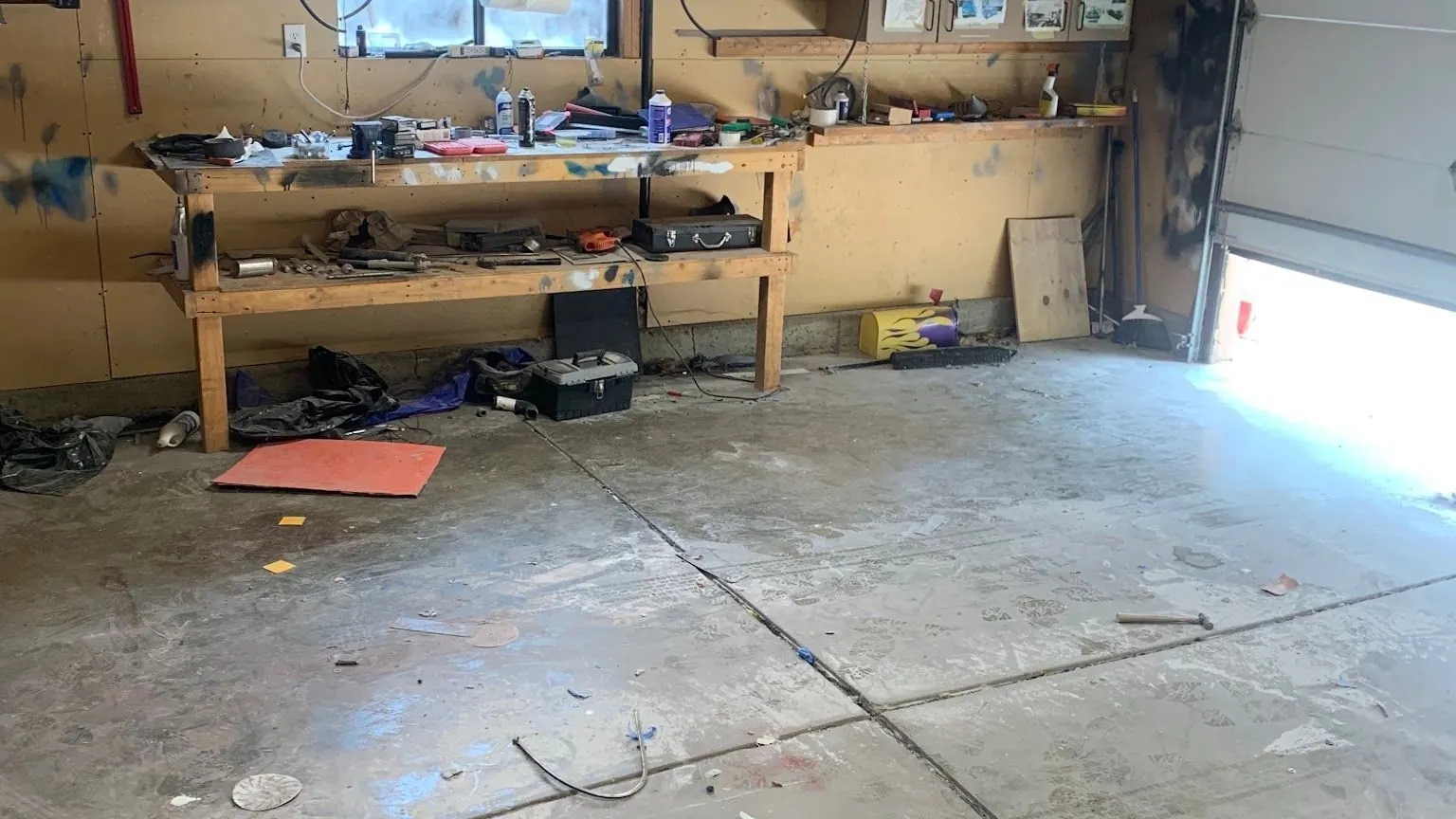 A cluttered garage workshop with a workbench of tools and parts