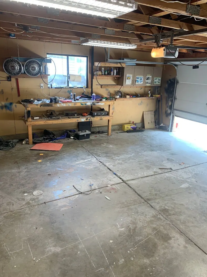 A cluttered garage workshop with a workbench of tools and parts